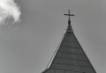 Grayscale shot of a church steeple with a cross against a cloudy sky Royalty Free Stock Photo