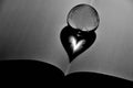 Grayscale shot of a crystal globe shaped ball with a heart reflection