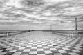 Grayscale shot of an empty square under a cloudy sky