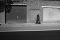 Grayscale shot of a female walking down the street wearing a mask