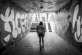 Grayscale shot of a female walking in a tunnel with graffiti walls in Seligenstadt, Germany