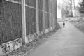 Grayscale shot of a footpath next to a sound barrier wall with a standing boy in Poznan, Poland