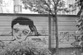 Grayscale shot of a graffiti of a person with cropped hair on a noise barrier in Essen, Germany