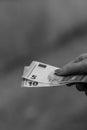 Grayscale shot of a hand giving EURO banknotes. Concept of rich businesspeople, savings, and wealth