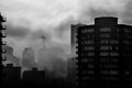 Grayscale shot of high urban skyscrapers under a cloudy gloomy sky