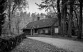 Grayscale shot of a large old wooden cabin in the woods