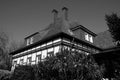 Grayscale shot of a modern beautiful house surrounded by greens and trees