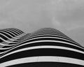 Grayscale shot of a modern curved building under a cloudy sky