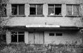 Grayscale shot of an old abandoned house with broken glass windows