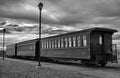 Grayscale shot of an old abandoned train under a cloudy sky