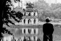 Grayscale shot of a person looking at the Turtle Tower in central Hanoi, Vietnam Royalty Free Stock Photo