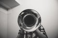 Grayscale shot of a person playing the trumpet with the bell side facing the camera