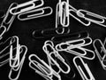 Grayscale shot of a pile of scattered paperclips on a black table