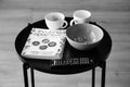 Grayscale shot of a Polish cooking book next to bowl and coffee cups on a small round table