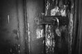 Grayscale shot of a rusty padlock hanging on an old wooden door Royalty Free Stock Photo