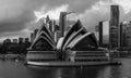 Grayscale shot of the Sydney Opera House with Sydney Tower in the background from the harbor.