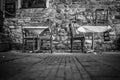 Grayscale shot of table and chairs on the sidewalk Royalty Free Stock Photo