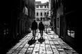 Grayscale shot of two men walking down an alley casting shadows on the foreground Royalty Free Stock Photo