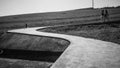 Grayscale shot of two women walking along a narrow curving path in the countryside