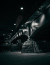 Grayscale shot in a vertical format of an urban bridge in the city at night