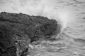 Grayscale shot of water hitting a stone