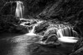 Grayscale shot of a waterfall surrounded with rocks Royalty Free Stock Photo