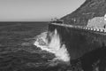 Grayscale shot of a wave breaker at the coastline road Royalty Free Stock Photo