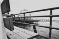 Grayscale shot of wooden bench on the pier of Santa Monica port, California with sea