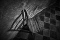 Grayscale shot of a wooden chair in the surface of a diamond tiled shape in the background Royalty Free Stock Photo