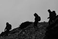 Grayscale of silhouettes of trekkers on the rocky mountain slope Royalty Free Stock Photo