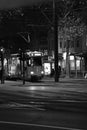 Grayscale of a tram going through town streets at night on the street