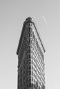 Grayscale vertical shot of a Flatiron Building in New York City with a clear sky in the background