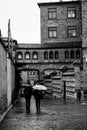 Grayscale vertical shot of two persons walking in the street with a beautiful building