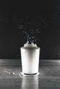 Grayscale vertical view of a white liquid splash in a glass cup