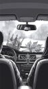 Grayscale view from car interior showing driver and passenger with symbolic items on dashboard Royalty Free Stock Photo