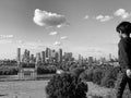 Grayscale of a young boy on a hilltop with a view of a Greenwich Park and Canary Wharf, London, UK