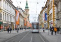 Graz/Austria - February 02, 2020: Herrengasse street with shops and modern tram and Parish Church Stadtpfarrkirche in the Royalty Free Stock Photo