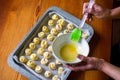 Greasing the baking dough with egg yolk and silicone brush. There is an egg yolk in plate. Baking in the shape of a rose