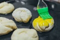 Greasing round dough close up. Round dough for a fancy cake greasing by green brush.