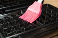 Greasing a waffle iron with a pink silicone brush Royalty Free Stock Photo