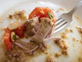 Greasy plate with fork, pork, tomatoes and buckwheat leftovers