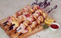 Greasy raw pork with skewered potatoes, barbecue with lemon and sauce on a wooden chopping Board close-up on the table