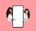 Great App. Cheerful Multiethnic Females Pointing At Big Blank Smartphone Screen Royalty Free Stock Photo