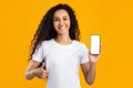 Woman Showing Cellphone Empty Screen Gesturing Thumbs Up, Yellow Background Royalty Free Stock Photo