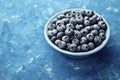 Great bilberry or blueberry in plate on blue rustic background. Vintage style.