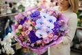 Great bouquet of different fresh flowers packed in purple paper in woman hands Royalty Free Stock Photo