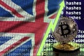 Great britain flag and rising green arrow on bitcoin mining screen and two physical golden bitcoins