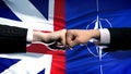 Great Britain vs NATO conflict, fists on flag background, diplomatic crisis Royalty Free Stock Photo