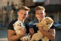 Great companions. Happy twins with muscular look. Twins men hold pedigree dogs. Muscular men with dog pets. Spitz dogs