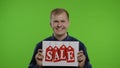 Great discounts. Happy cheerful blonde man in blue shirt showing Sale word advertisement inscription